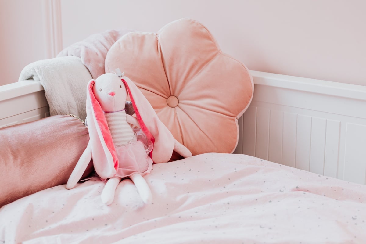 Cute plush toys and pink blankets in cozy bedroom interior for
