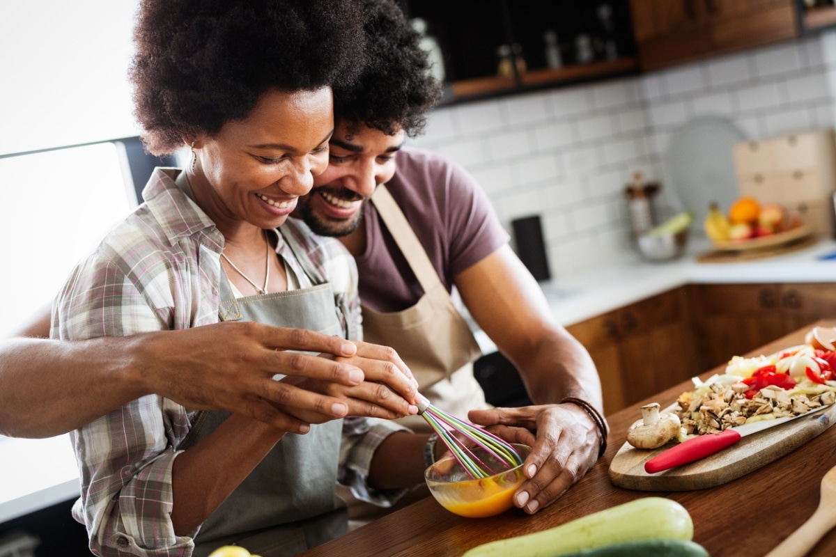 Portrait of happy young couple cooking together in the kitchen at home.