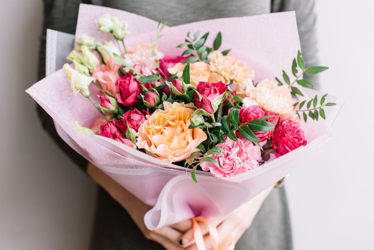 A woman holding a big and colourful bouquet of flowers for Valentine's Day.