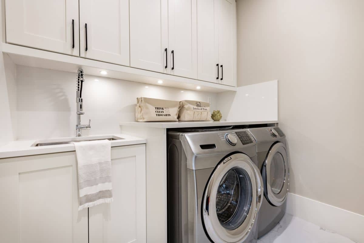 Under-cabinet lights in clean, bright laundry room with washer and dryer