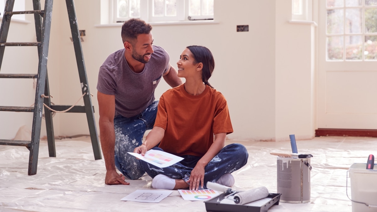 A couple sitting on the floor and preparing to paint a room for their home renovation.